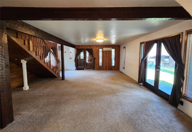 unfurnished living room with stairway, an AC wall unit, french doors, and carpet