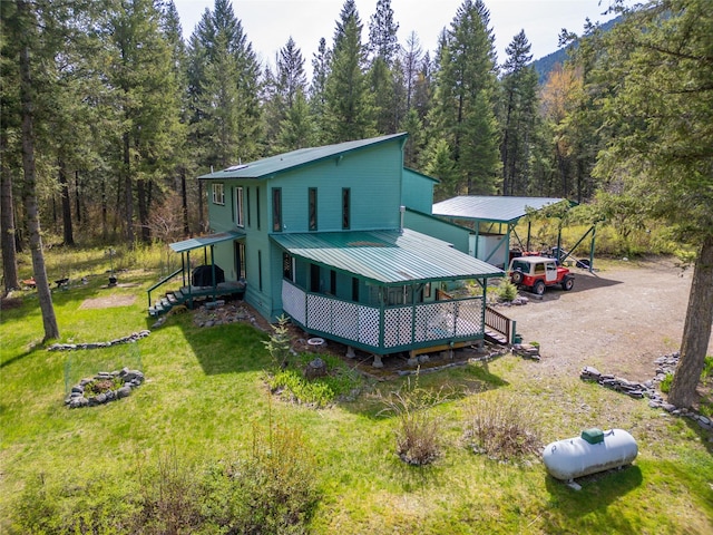 back of house with a yard, a wooded view, and a carport