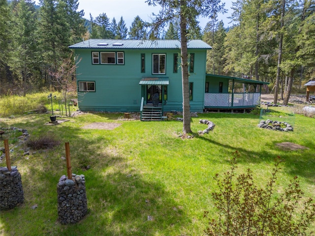 back of property with a lawn, a view of trees, and metal roof