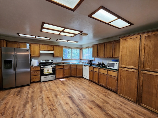 kitchen featuring under cabinet range hood, brown cabinets, appliances with stainless steel finishes, and light wood-type flooring