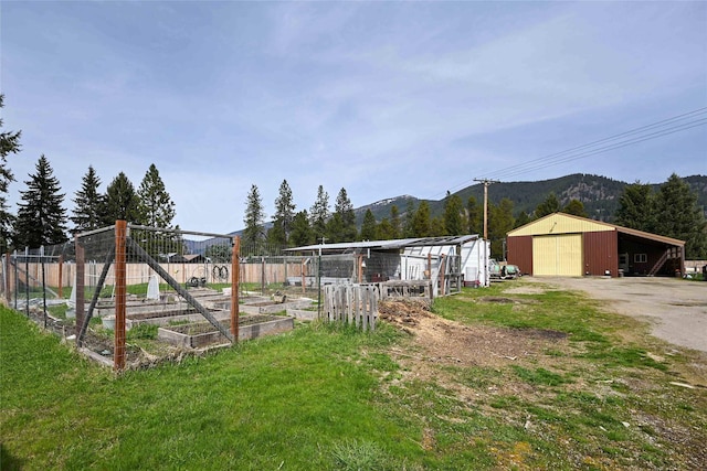 57 Fir St, Trout Creek, MT 59874 - view of yard featuring a mountain view, an outbuilding, a garden, driveway, and a detached garage