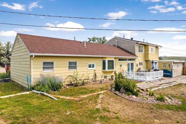 rear view of house with a yard, fence, a deck, and a shingled roof
