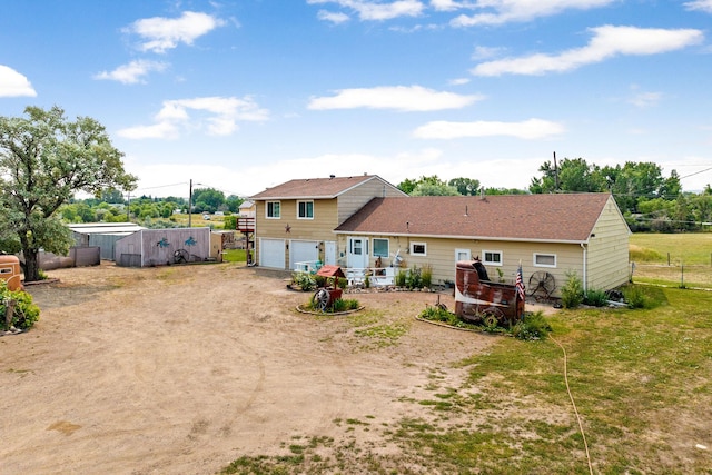 rear view of property with an attached garage, fence, and driveway