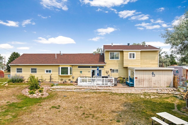 back of house with fence, a lawn, a wooden deck, and a patio area