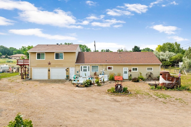 back of property featuring driveway, fence, and a garage