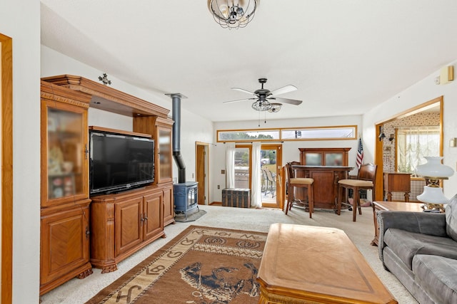 living room featuring light colored carpet, a wealth of natural light, and a wood stove