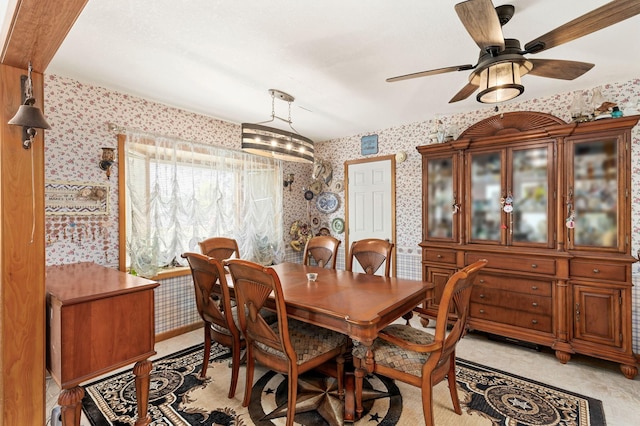 dining space featuring ceiling fan and wallpapered walls