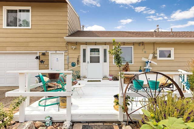 rear view of property featuring a garage, a shingled roof, and a deck