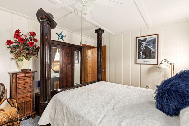 bedroom with a ceiling fan, carpet floors, vaulted ceiling, and a decorative wall