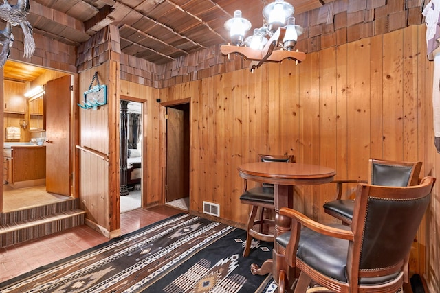 interior space featuring visible vents, wood walls, and a notable chandelier