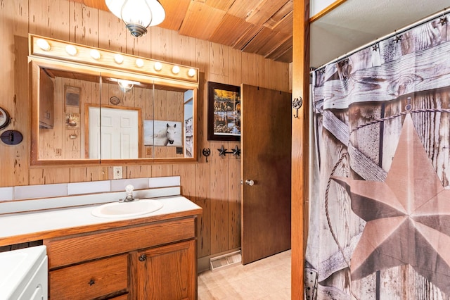 bathroom featuring a shower with curtain, vanity, and wooden walls