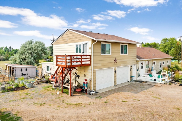 back of property with stairway, driveway, a deck, a shingled roof, and an attached garage