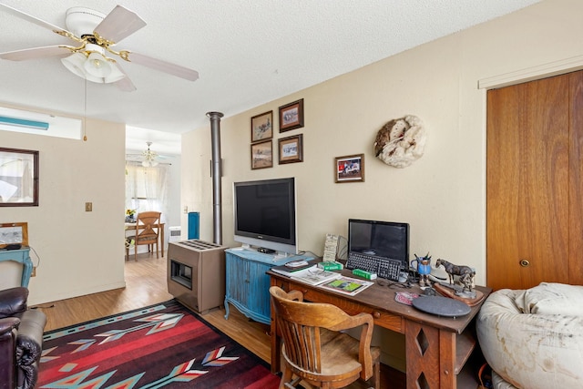 office area featuring a ceiling fan, light wood-style floors, and a textured ceiling