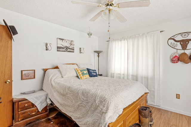 bedroom with light wood-style floors, a textured ceiling, and a ceiling fan