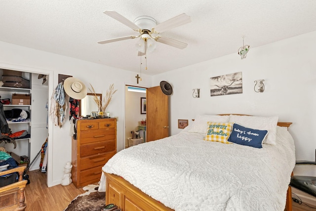 bedroom with light wood-style floors, ceiling fan, a closet, and a spacious closet