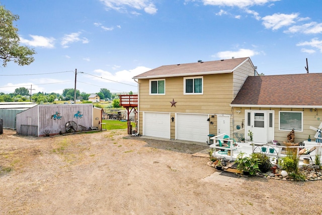 rear view of property with an attached garage, a shingled roof, and driveway