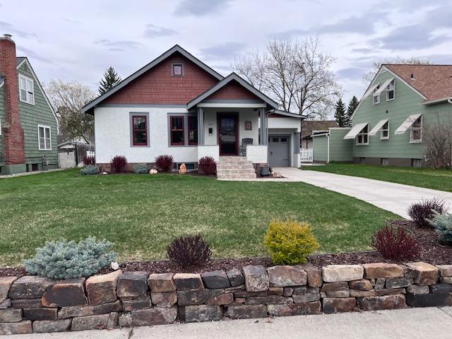 view of front of home with concrete driveway, a front lawn, and a garage