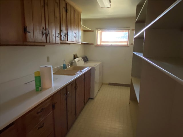 laundry room featuring light floors, separate washer and dryer, cabinet space, and a sink