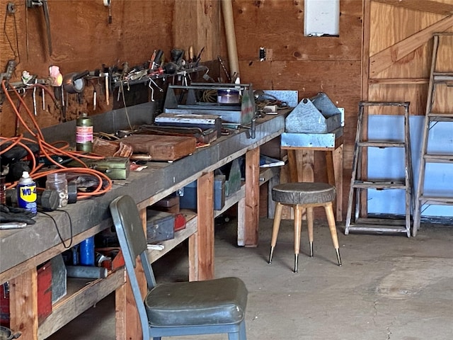 misc room featuring concrete floors, wood walls, and a workshop area