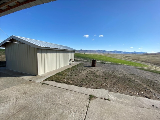 view of property exterior with a mountain view, an outbuilding, and metal roof