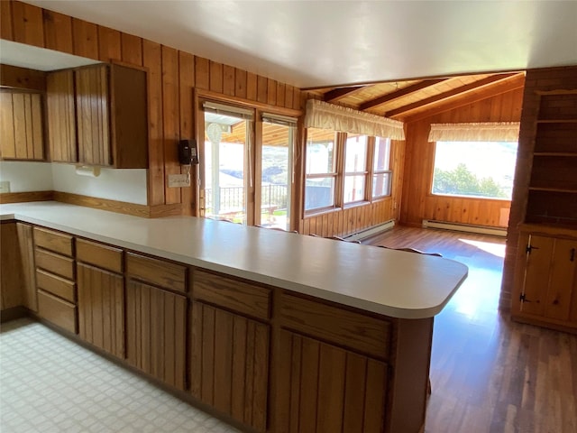 kitchen with a peninsula, light countertops, wood walls, and baseboard heating