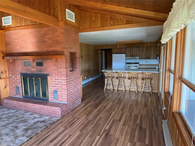 unfurnished living room with wood walls, vaulted ceiling with beams, visible vents, and dark wood-type flooring