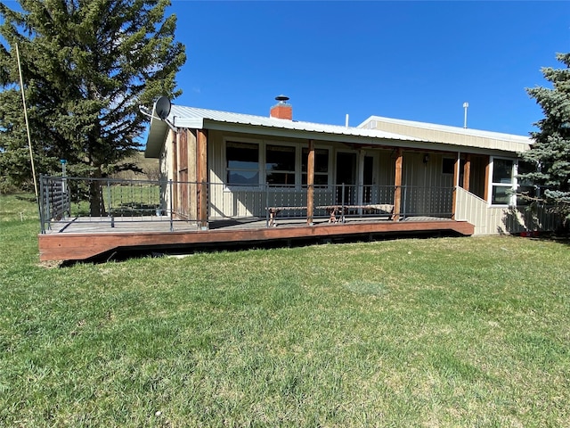 back of property with a lawn, a chimney, and a wooden deck