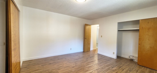unfurnished bedroom with baseboards, wood finished floors, a textured ceiling, and a closet