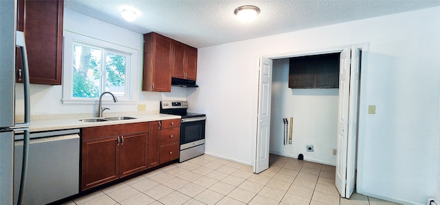 kitchen with a sink, a textured ceiling, appliances with stainless steel finishes, light countertops, and under cabinet range hood