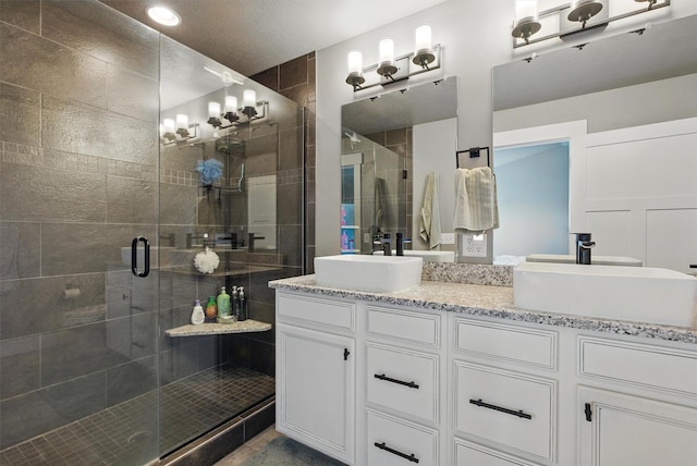 bathroom with a shower stall, a sink, and double vanity