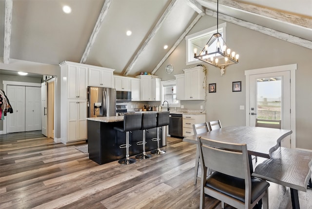 kitchen with white cabinets, stainless steel appliances, a center island, and high vaulted ceiling