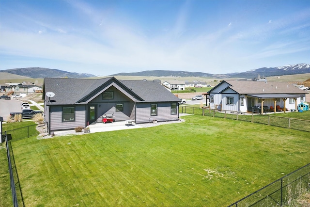 back of property featuring a yard, a mountain view, a patio area, and a fenced backyard