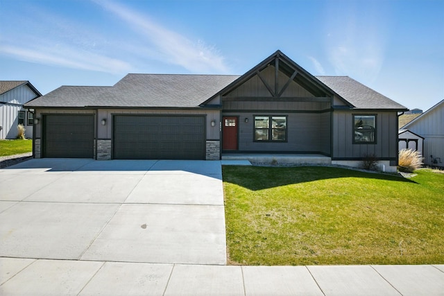 view of front facade featuring a garage, concrete driveway, board and batten siding, a front yard, and roof with shingles