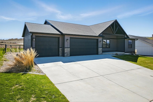 view of front facade with a front lawn, concrete driveway, an attached garage, stone siding, and roof with shingles