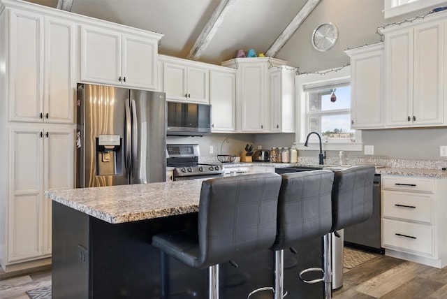 kitchen featuring white cabinets, light wood-style floors, vaulted ceiling, and stainless steel appliances