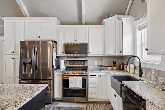 kitchen featuring white cabinetry, light stone countertops, stainless steel appliances, and a sink