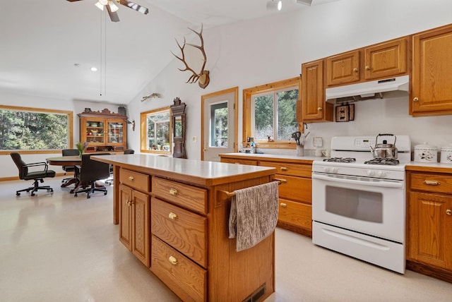 1000 Kelley Rd, Columbia Falls, MT 59912 - kitchen featuring white gas range, under cabinet range hood, a center island, vaulted ceiling, and light countertops