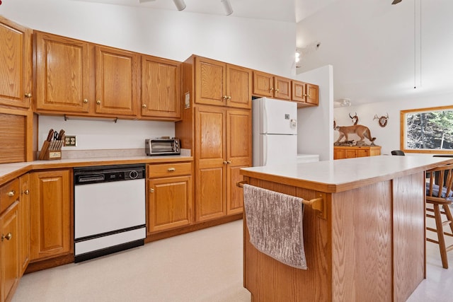 1000 Kelley Rd, Columbia Falls, MT 59912 - kitchen with white appliances, a center island, light countertops, brown cabinetry, and a kitchen breakfast bar