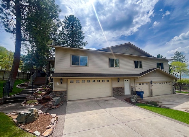 1023 Whitaker Dr Unit A, Missoula, MT 59803 - view of front of property featuring a garage, concrete driveway, stone siding, stairs, and fence