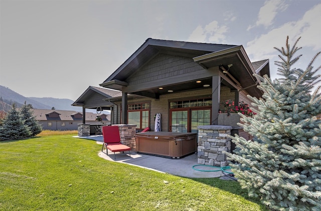 780 Anglers Bend Way, Missoula, MT 59802 - rear view of property featuring a patio area, a lawn, stone siding, a mountain view, and a hot tub