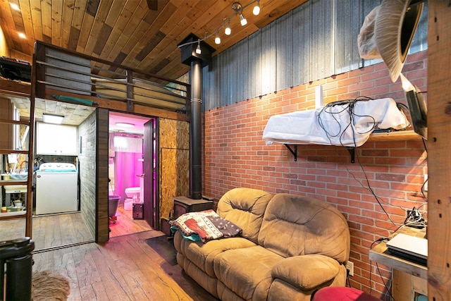 living room with wood-type flooring, wooden ceiling, washer / clothes dryer, and a wood stove