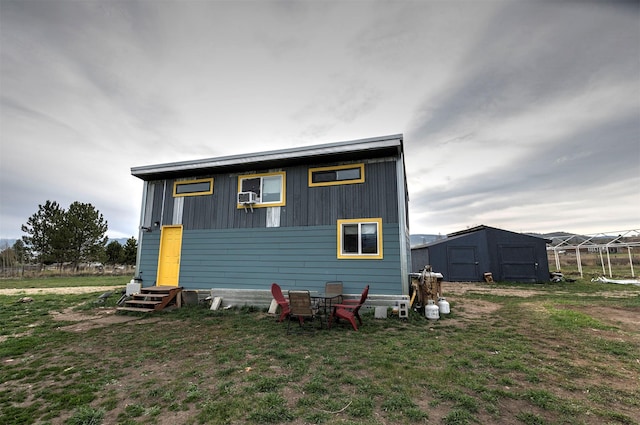 back of property featuring a lawn, an outdoor structure, a shed, and entry steps