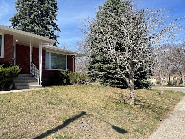 view of property exterior with brick siding and a yard