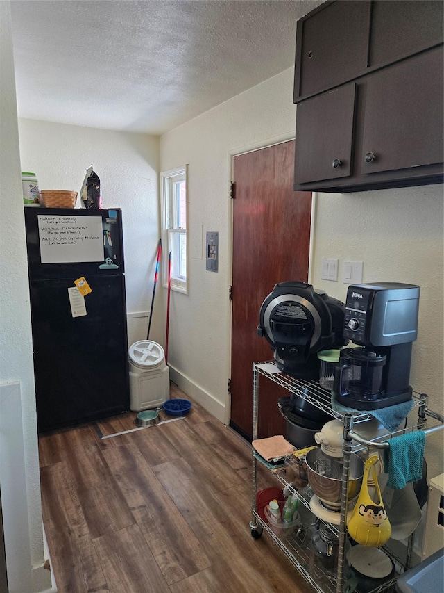 kitchen featuring baseboards, wood finished floors, freestanding refrigerator, and a textured ceiling
