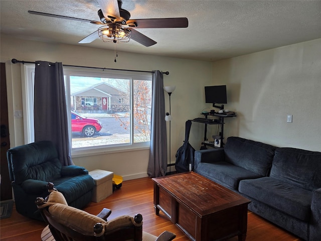 living room with wood finished floors, a textured ceiling, baseboards, and ceiling fan