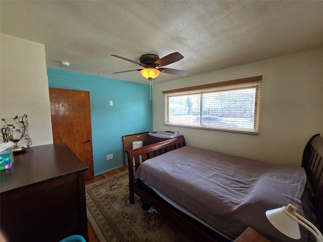 bedroom with wood finished floors, a textured ceiling, and a ceiling fan