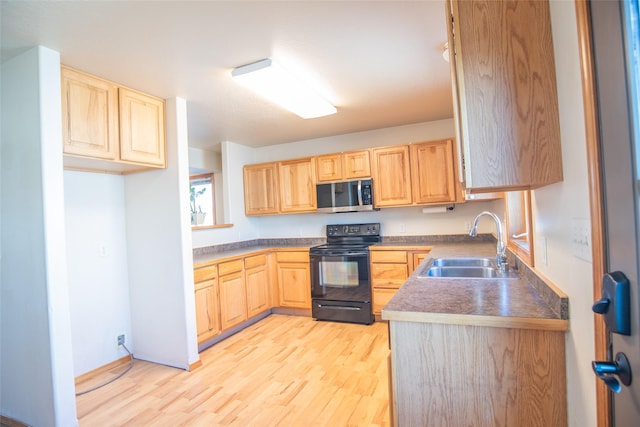 2226 Burlington Ave Unit A, Missoula, MT 59801 - kitchen with light brown cabinetry, stainless steel microwave, black electric range, a sink, and light wood-style flooring