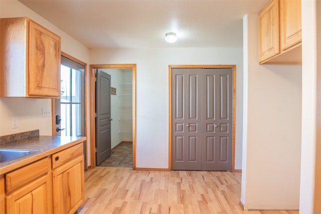 2226 Burlington Ave Unit A, Missoula, MT 59801 - kitchen featuring light brown cabinetry, dark countertops, a sink, light wood finished floors, and baseboards