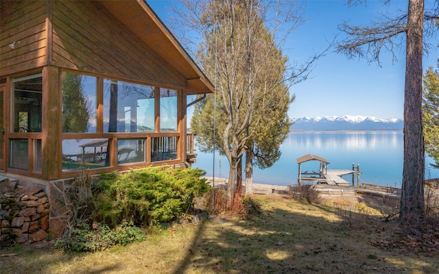 view of yard featuring a sunroom and a water and mountain view