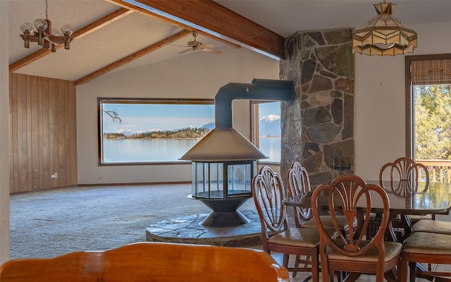 dining space with wooden walls, carpet floors, vaulted ceiling with beams, and ceiling fan with notable chandelier